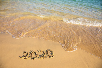2020 summer beach holiday season written on golden sand washed away wave - new season lettering on sand - numbers 2020 year travel vacation sandy wavy water yellow blue azure aquamarine turquoise
