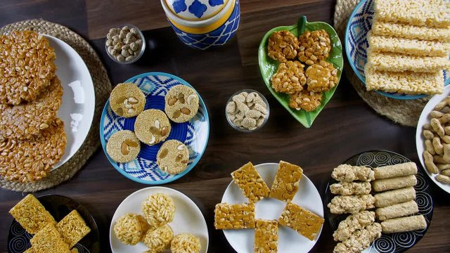 Beautifully plated fresh sweets on the special occasion of Lohri the festival of India. Top view shot of different sweets like peanuts chikki  crispy gajak  murmura ladoo  rewri  bhujia chikki  and...