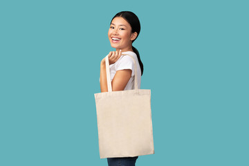 Smiling Asian Girl Holding White Eco Bag Standing, Turquoise Background