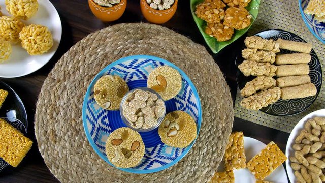 Beautifully plated homemade sweets consumed during Lohri festival - winter season. Top view shot of dry fruit gajaks with a bowl of rewri rotating on a turntable surrounded by different Lohri items...