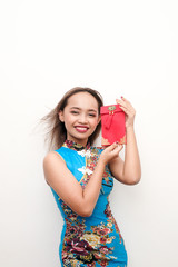 Young Female wearing a traditional blue qipao or cheongsam celebrating Chinese New Year recieving Ang Pao or Money in red envelope.