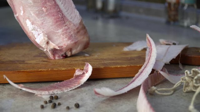 with a sharp knife on a wooden Board we cut layers of fresh frozen fish