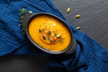 Healthy food concept Warm mix vegetable soup and pumpkin seeds in black ceramic cup with copy space