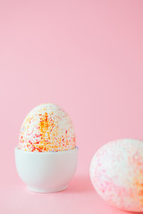 Two easter eggs decorated with watercolour aquarelle, minimalism style on plain pink background. Easter holiday decorations with copy space