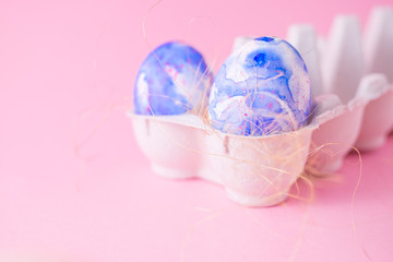 Two easter eggs decorated with classic blue watercolour (aquarelle) in carton, minimalism style on plain pink background. Easter holiday decorations with copy space