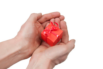 the palms of the right and left hands together hold a red gift box tied with a red shiny ribbon on a white background top view