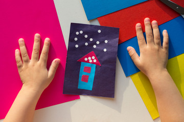 Top view of cutout with the house and snow made by child and child hands