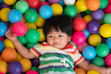 Fototapeta na wymiar Happy Asian girl (one and half years olds) playing little colorful balls in pool ball. The concept of playing is the best learning for children.