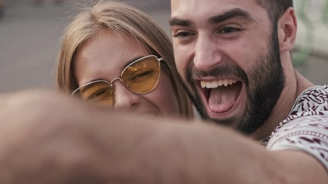 Positive couple man and woman are taking a selfie outdoors in an amusement park