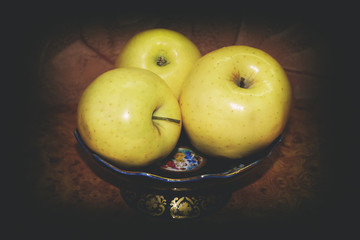 Golden yellow apple on a plate on a dark background close-up