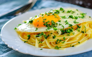 fried egg with Linguine pasta in white plate on wooden table