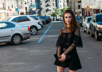 Fototapeta premium portrait of a girl, brunette, in a black dress, in the arch, in the city. posing, walking. alone in the crowd, loneliness.sad