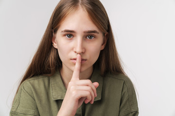 Photo of serious woman making silence gesture and looking at camera