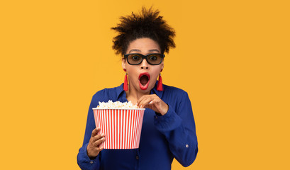 Shocked afro girl in 3d glasses watching movie with popcorn