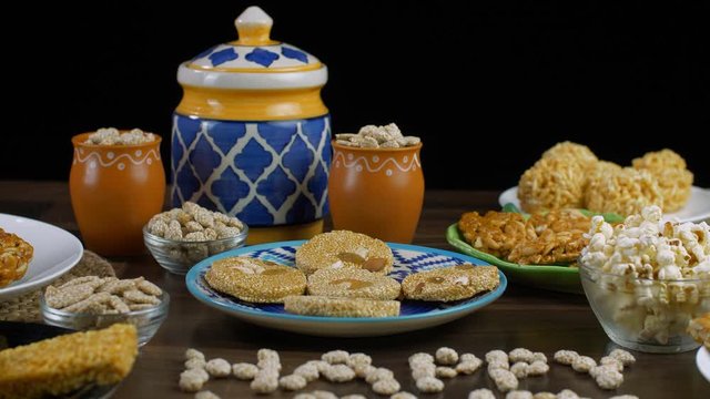 Closeup shot of Lohri items on the occasion of Lohri the harvest festival of India. Tilt shot of 'Happy Lohri' text written with rewri surrounded by til patti  bhujia chikki  popcorns  peanuts chik...
