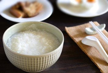 Fototapeta na wymiar Boiled rice in gray bowl with food for eating which has chopstick with spoon all put on dark wooden table