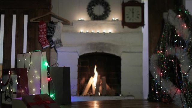 Gifts by the fireplace on Christmas Eve. A charging Christmas tree flashes lights. A real fire burns out in the fireplace.