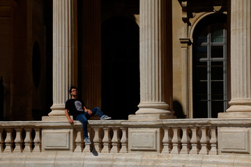 Obraz premium Male teenage model sitting thoughtfully between ancient columns