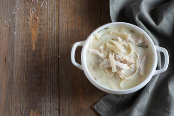 Turkish hot soup with chicken and noodles in a white plate on a wooden table