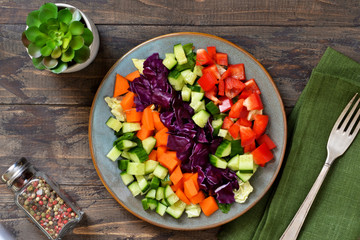 Vegetable cobs salad with stamates, cucumber, pepper, spinach and olive sauce on a wooden background. Salad is a rainbow.