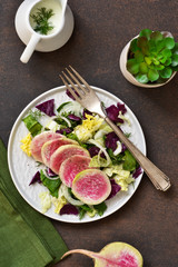 Salad with spinach, cabbage and radish on a rustic, concrete background. Proper nutrition.