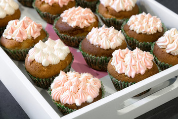 Cupcakes with pink cream on a white tray.