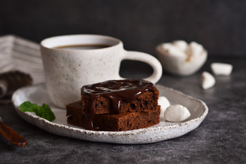 Chocolate brownie with coffee and marshmallows on a concrete background.