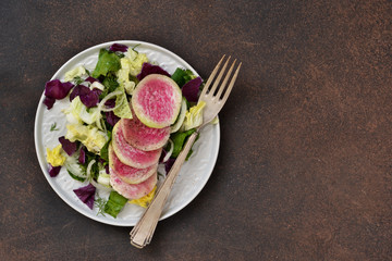 Salad with spinach, cabbage and radish on a rustic, concrete background. Proper nutrition.