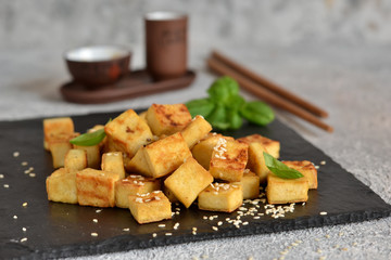 Fried tofu with soy sauce on a wooden board.