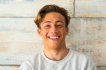 close up of beautiful teenager smiling and laughing alone at home - portrait of face of young man - obrazy, fototapety, plakaty