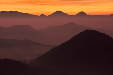 Fototapeta na wymiar Sunrise with silhouette of mountains under orange sky