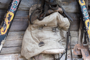 Horse saddle with pillow hangs on wooden house in the village.