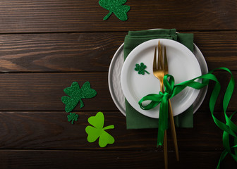 St. Patrick's Day green Shamrocks with fork, spoon, and napkin on rustic brown wood board...