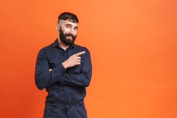 Image closeup of brunette man with nose jewelry pointing finger aside at copyspace