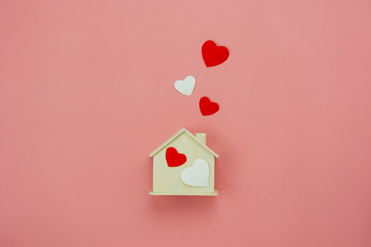 Table top view aerial image of decoration valentine's day background concept.Flat lay essential items colorful pastel love shape with wooden house on modern rustic pink paper.Mock up creative design.