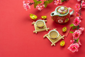 Chinese character means fortune and luck.Top view of Lunar New Year & Chinese New Year vacation concept background.Flat lay cup of tea with  red pocket money and pink cherry flower on red paper.