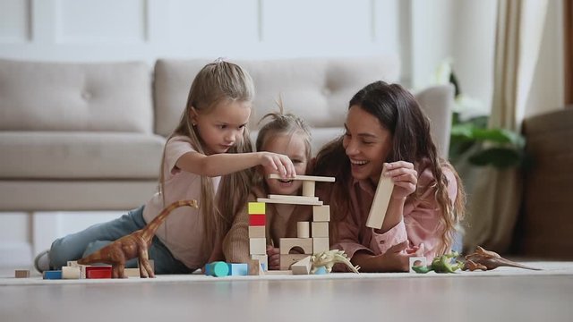 Happy mum babysitter play with children build castle of blocks