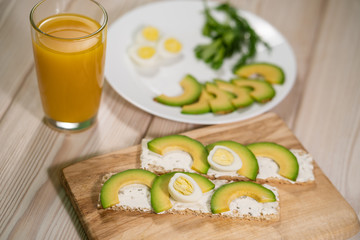 Breakfast avocado and egg toast, orange juice on wooden table. Healthy breakfast