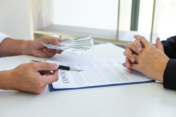 Businessman giving bribe money in the envelope of their partner to give success the deal contract...