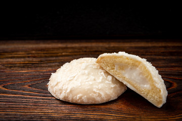 Biscuit cookies with coconut filling on dark wooden background.