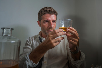 Fototapeta na wymiar alcoholic man in lose necktie drinking alcohol desperate and wasted looking at whiskey glass thoughtful drunk and depressed fighting his drinking addiction