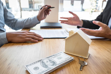 Real estate agent are presenting home loan and giving house, keys to customer after signing contract to buy house with approved property application form