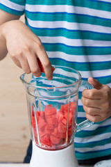 Hand put Watermelon cut in cube shape into food blender prepared for make juice