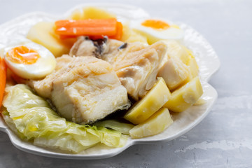 boiled fish with vegetables and boiled egg on white plate