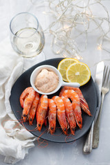 boiled shrimps with lemon and sauce on white dish on ceramic background