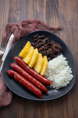 sausages with rice, black beans, and pineapple on dark dish