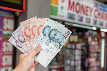 Hand holding Singapore dollar banknotes, currency exchange concept
