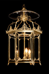Antique decorative hanging brass hall lantern lamp illuminating isolated on black