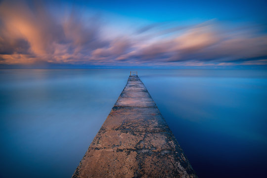 Long exposure seascape fine art photograph of pier on a sunrise in Paphos, Cyprus 