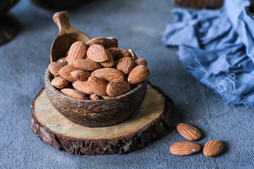 Photo of almond in the bowl on dark background. Almond on wooden board. Almond on gray background. Raw whole almond. Front view Almond. Images.